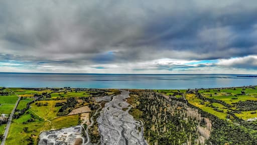 A panoramic photo of Hapuku river delta on the Pacific shore on the South Island of New Zealand under moody sky