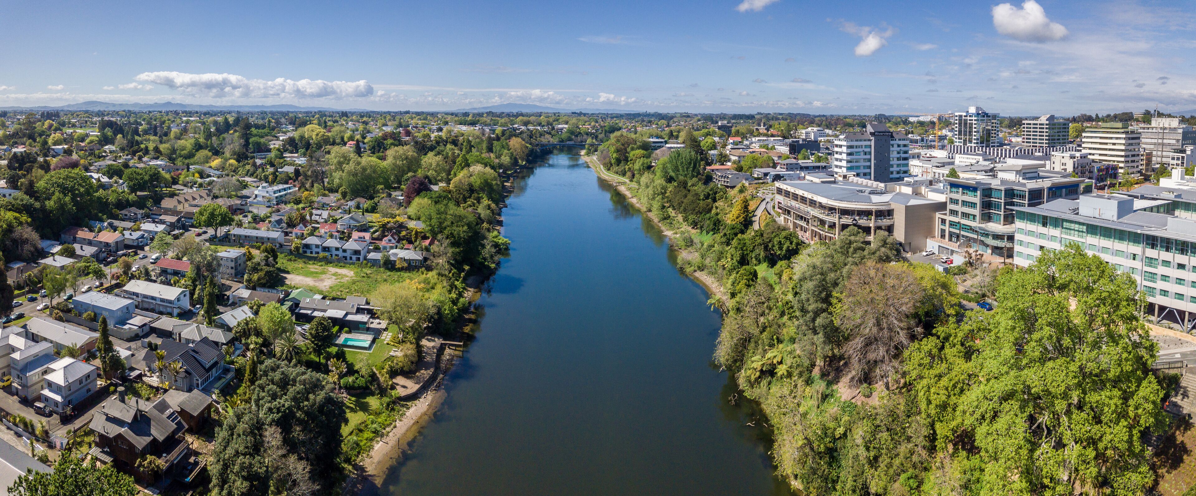 Un río serpentea por una ciudad con zonas residenciales y edificios modernos.