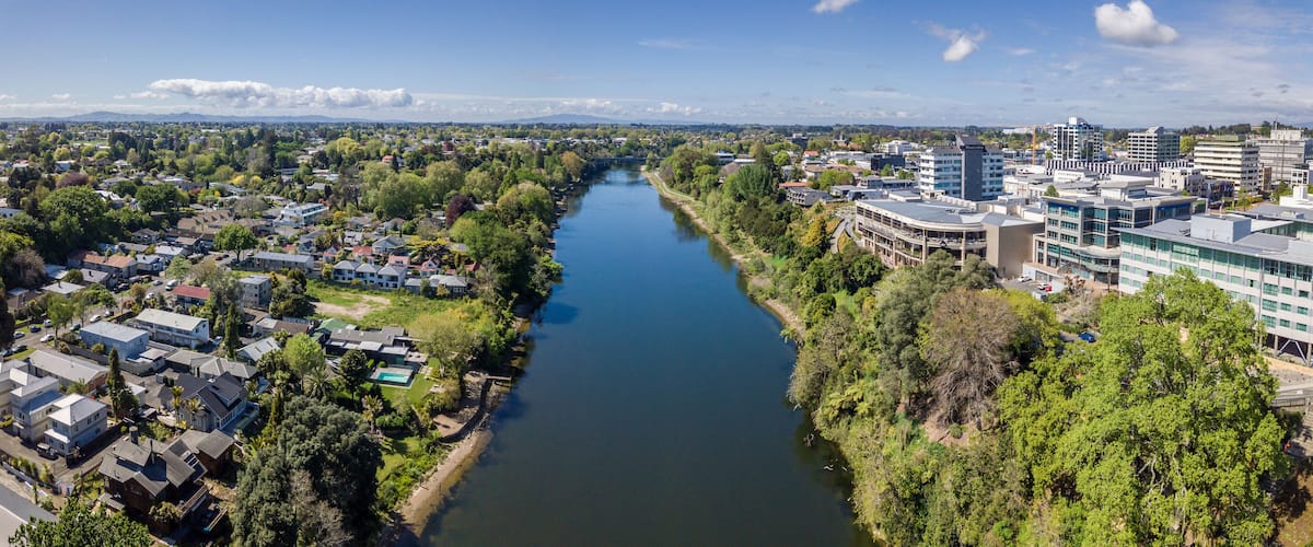 A river flowing through a city with residential areas and modern buildings.