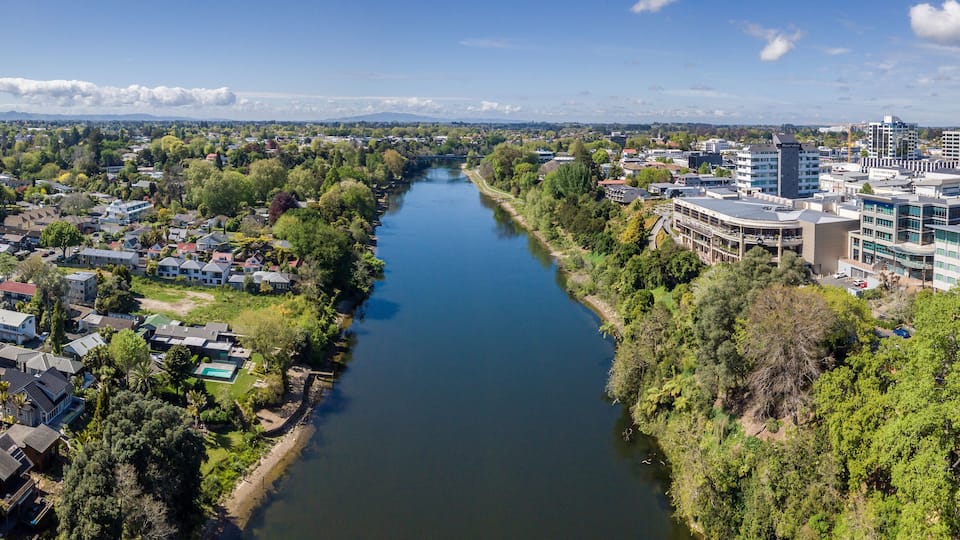 A river flowing through a city with residential areas and modern buildings.