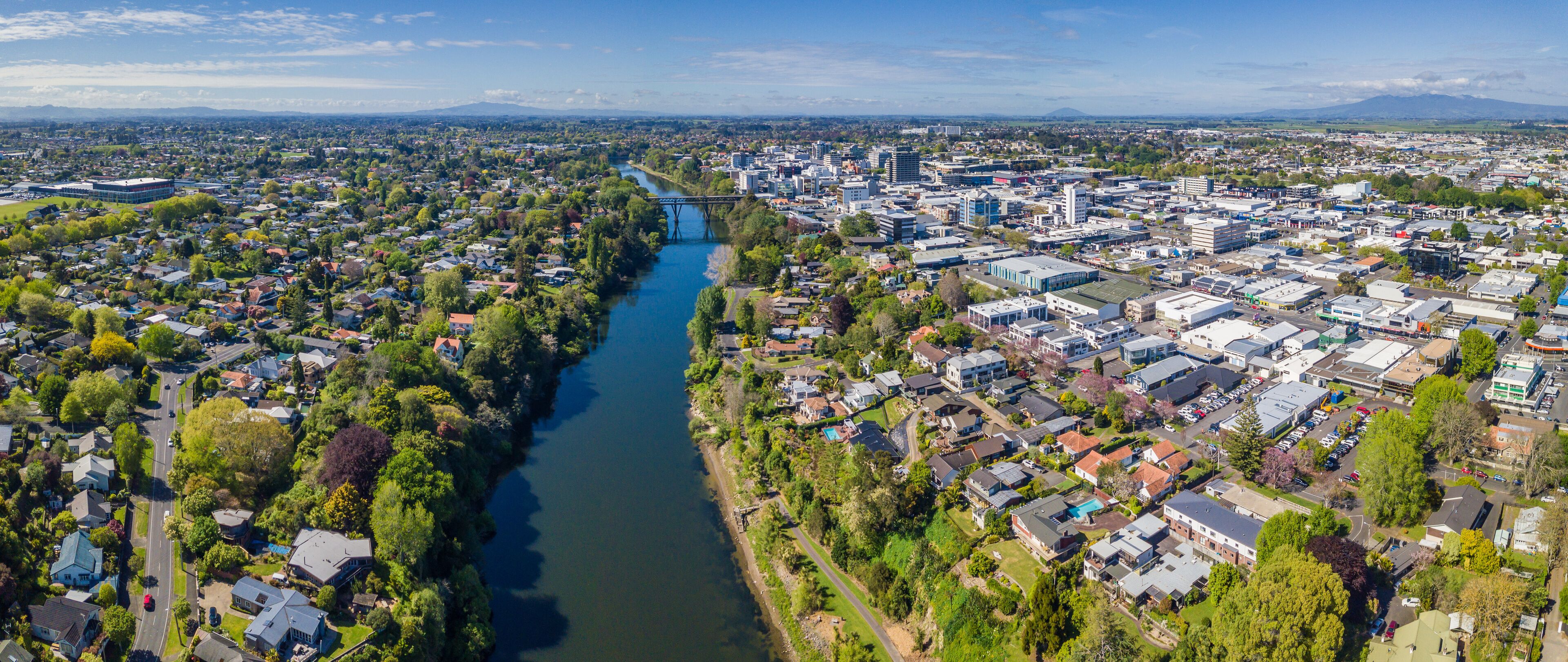 An aerial view of a city with a river running through it, surrounded by residential areas and commercial buildings.