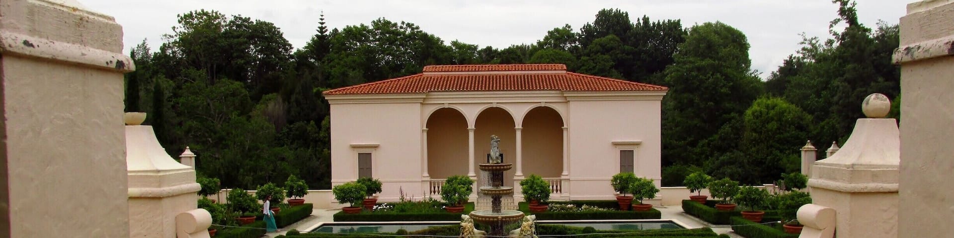 A classical building with a fountain and a pool in a formal garden.