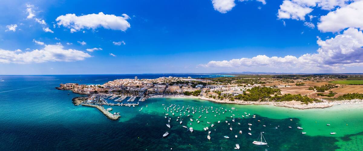 A coastal town with a marina, boats, and a clear blue sky.