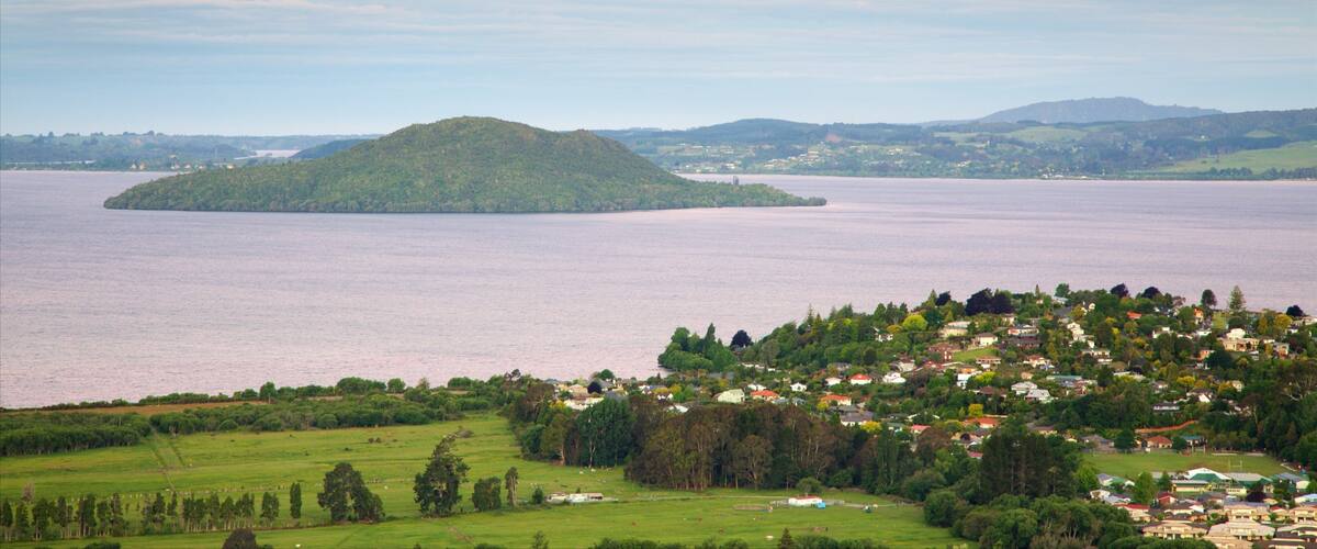 A coastal town with a large body of water, a small island, and rolling hills in the background.