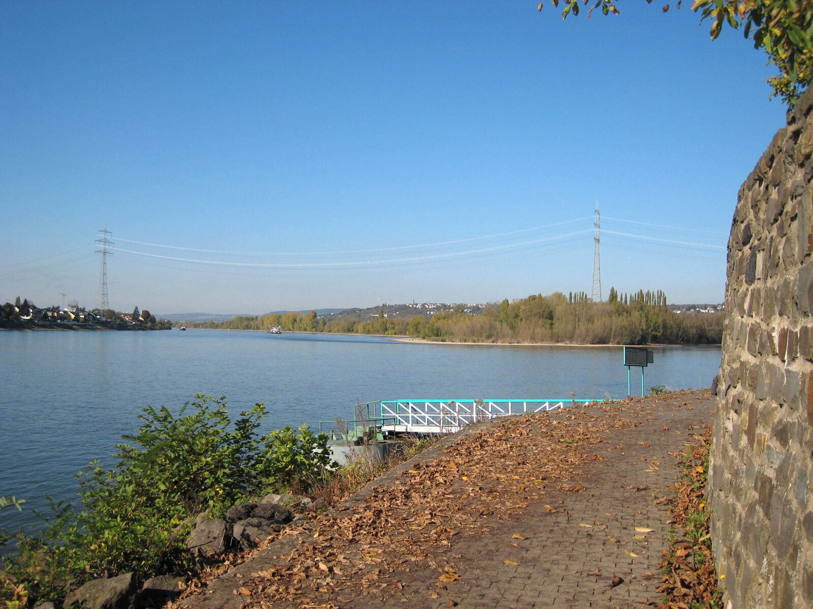 A river with a stone wall and a bridge in the background.