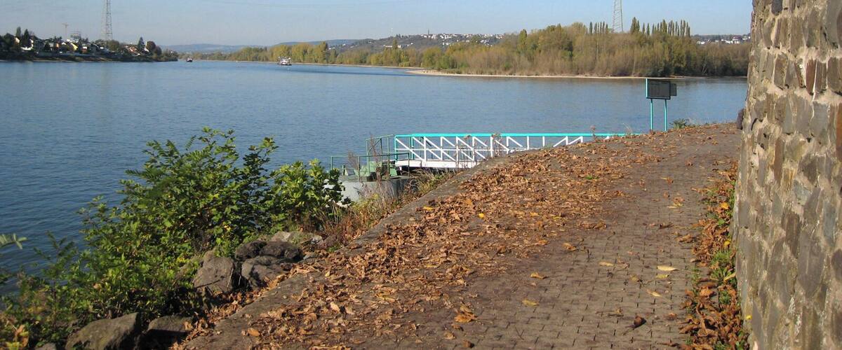 A river with a stone wall and a bridge in the background.