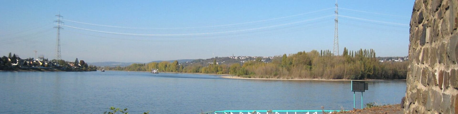 A river with a stone wall and a bridge in the background.