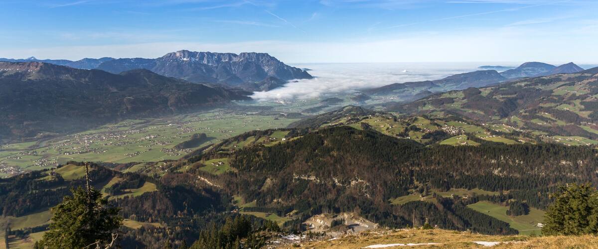 A mountainous landscape with a valley, a village, and a prominent mountain peak.