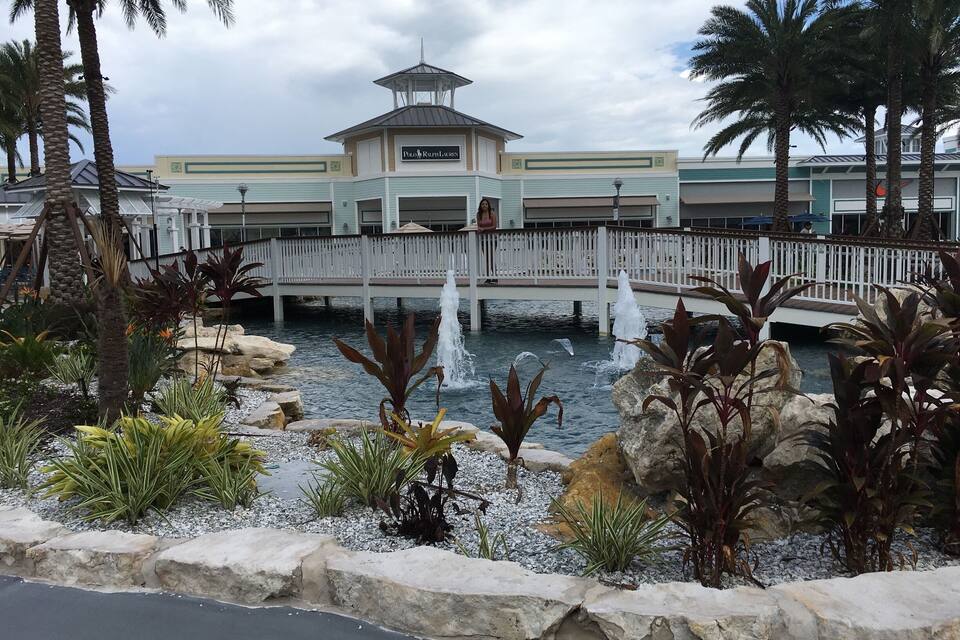 A waterfront area with a bridge, palm trees, a fountain, and a building labeled "Polo Ralph Lauren."