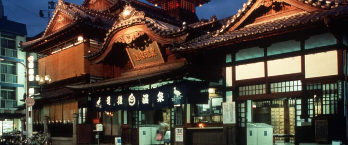 A traditional Japanese building with ornate wooden architecture and illuminated signs.