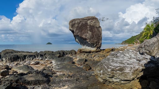 Large rock on rocky shoreline of a Fiji island panorama