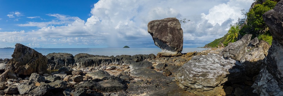 Large rock on rocky shoreline of a Fiji island panorama