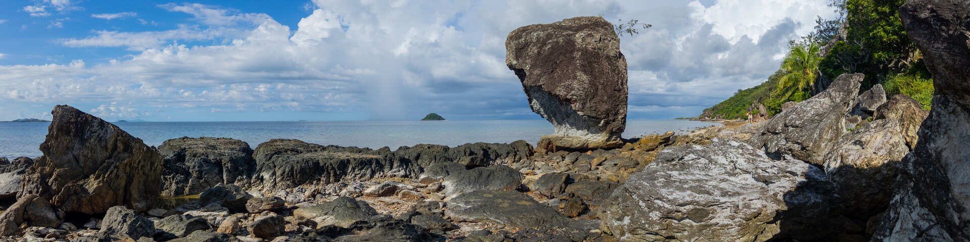 Large rock on rocky shoreline of a Fiji island panorama