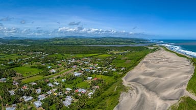 A coastal landscape with a sandy beach, a small village, and rolling hills in the background.