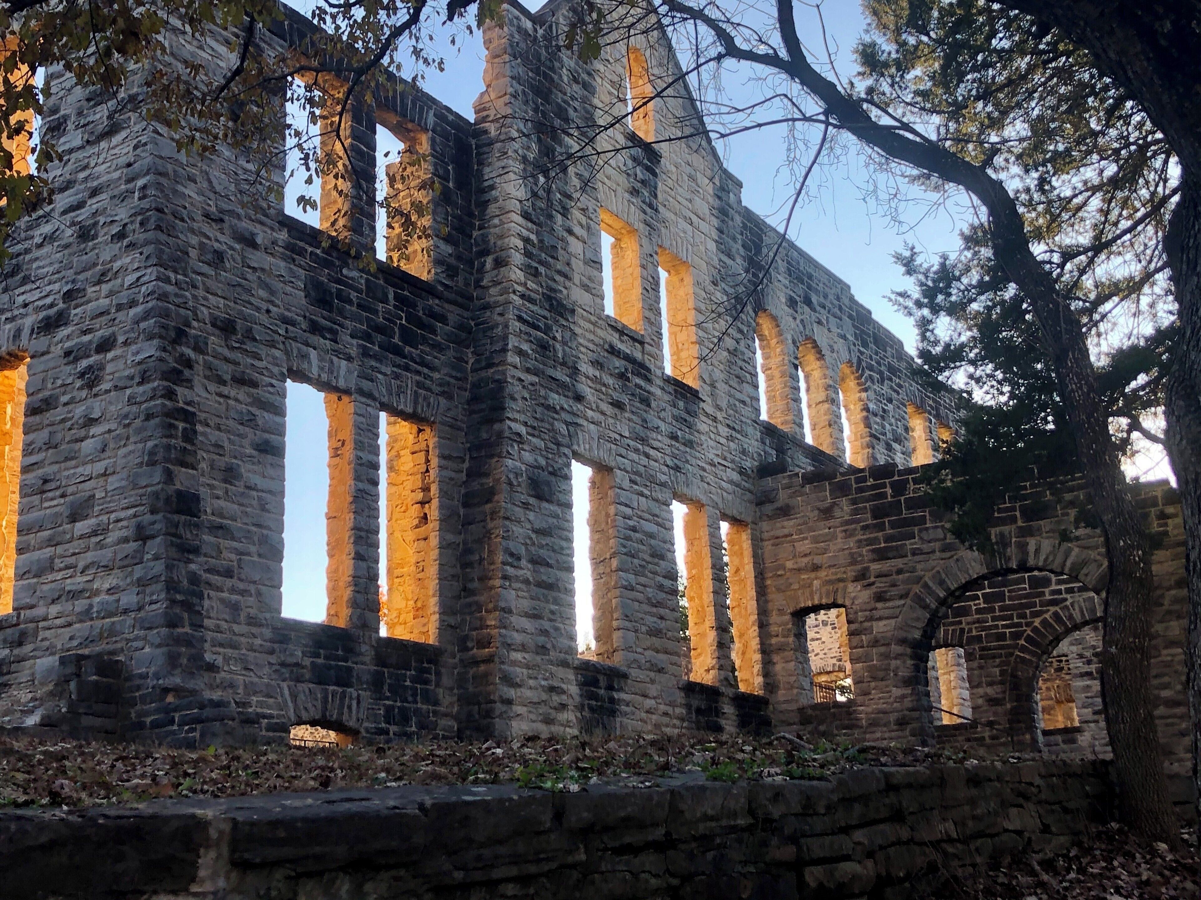 A historic stone building with arched windows and a brick archway.