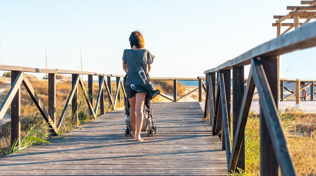 A young mother walking on the walkway of the Bateles beach in Conil de la Frontera, Cadiz. Andalusia