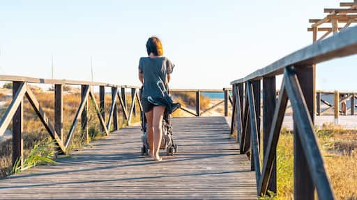A young mother walking on the walkway of the Bateles beach in Conil de la Frontera, Cadiz. Andalusia