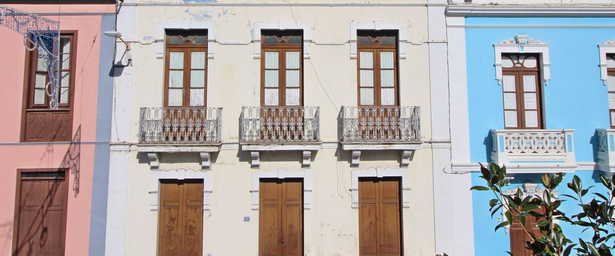 A row of colorful buildings with balconies and wooden doors.
