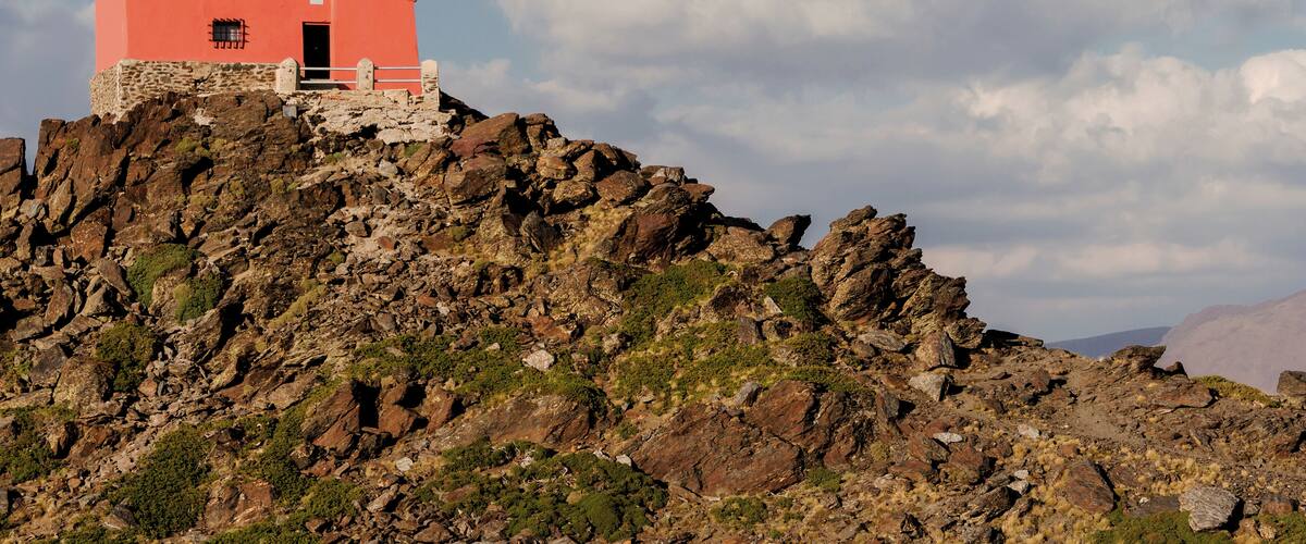 A red observatory on a rocky hill with a clear sky.