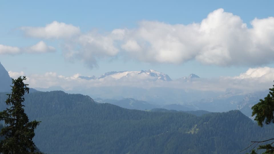A mountain range with snow-capped peaks and a forested valley.