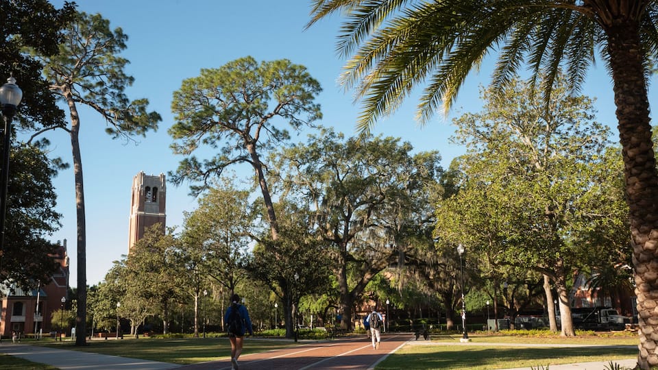 Students at the University of Florida walk through Plaza of the Americas with Century Tower in the background.