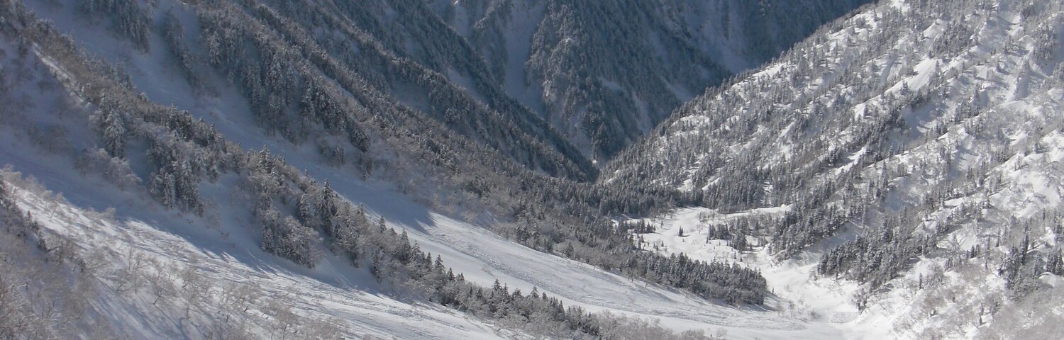 A snow-covered mountain range with a valley in the foreground.