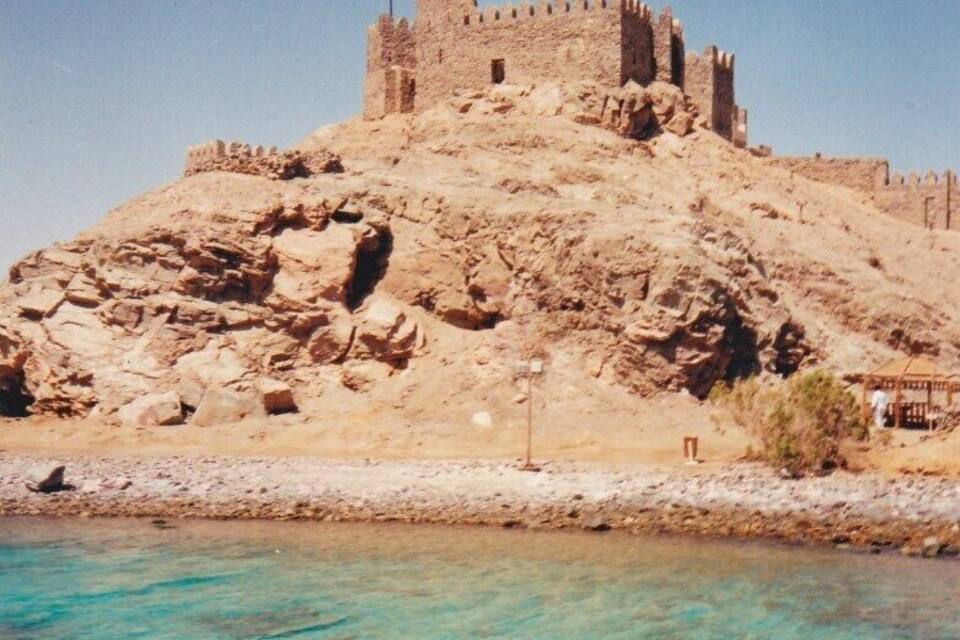 A castle on a rocky hill with a flag.