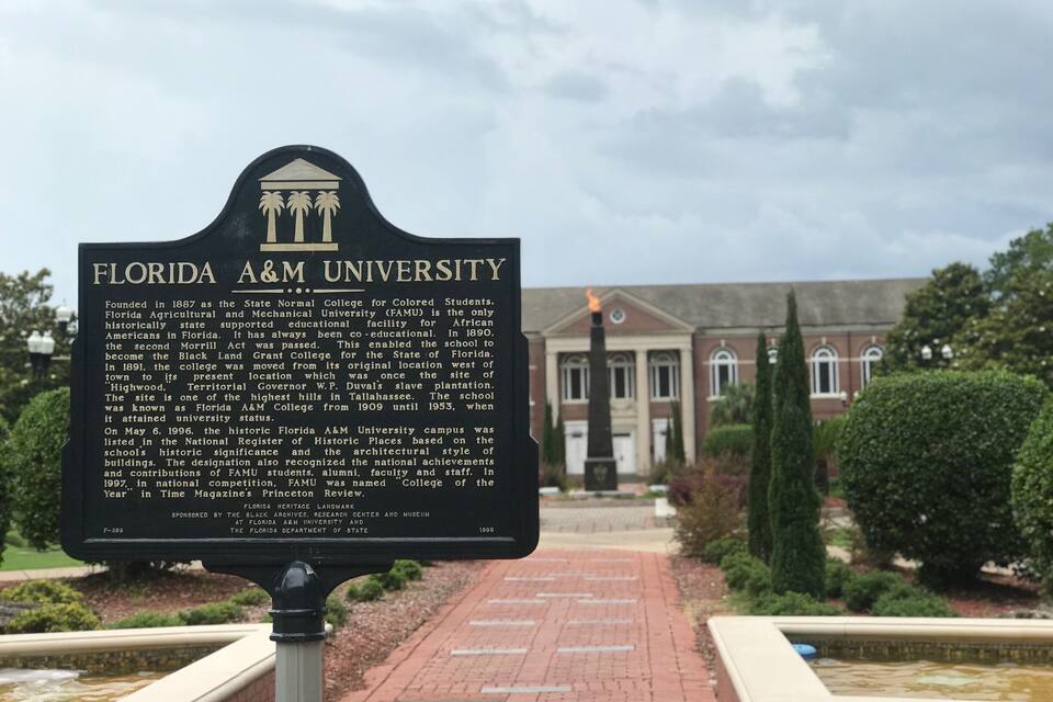 A historical marker for Florida A&M University with a brick pathway and a building in the background.