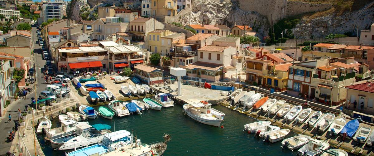 A coastal town with a marina filled with boats, historic buildings, and a prominent cliff.