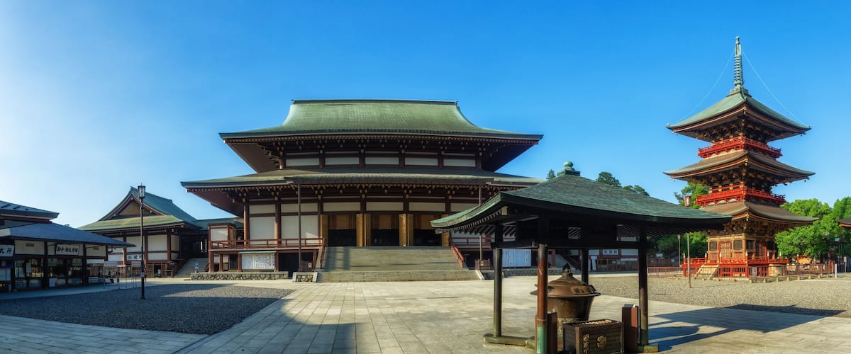 A traditional Japanese building with a large wooden structure and a pagoda in the background.
