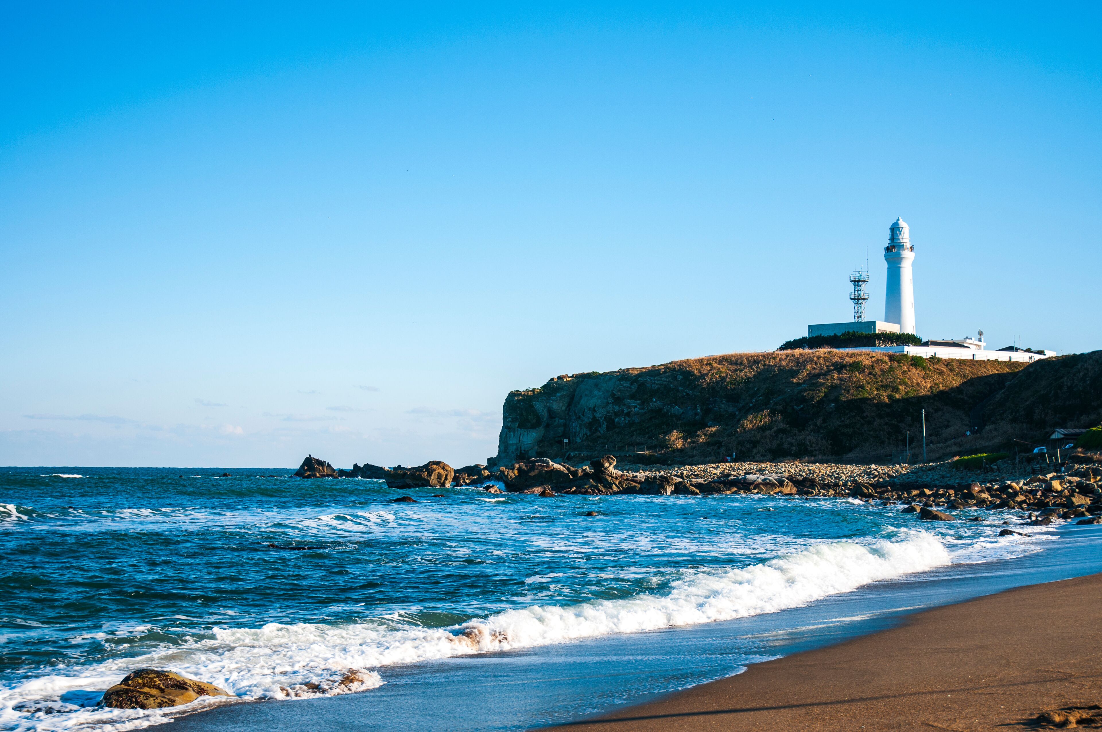 A lighthouse on a rocky cliff by the sea.