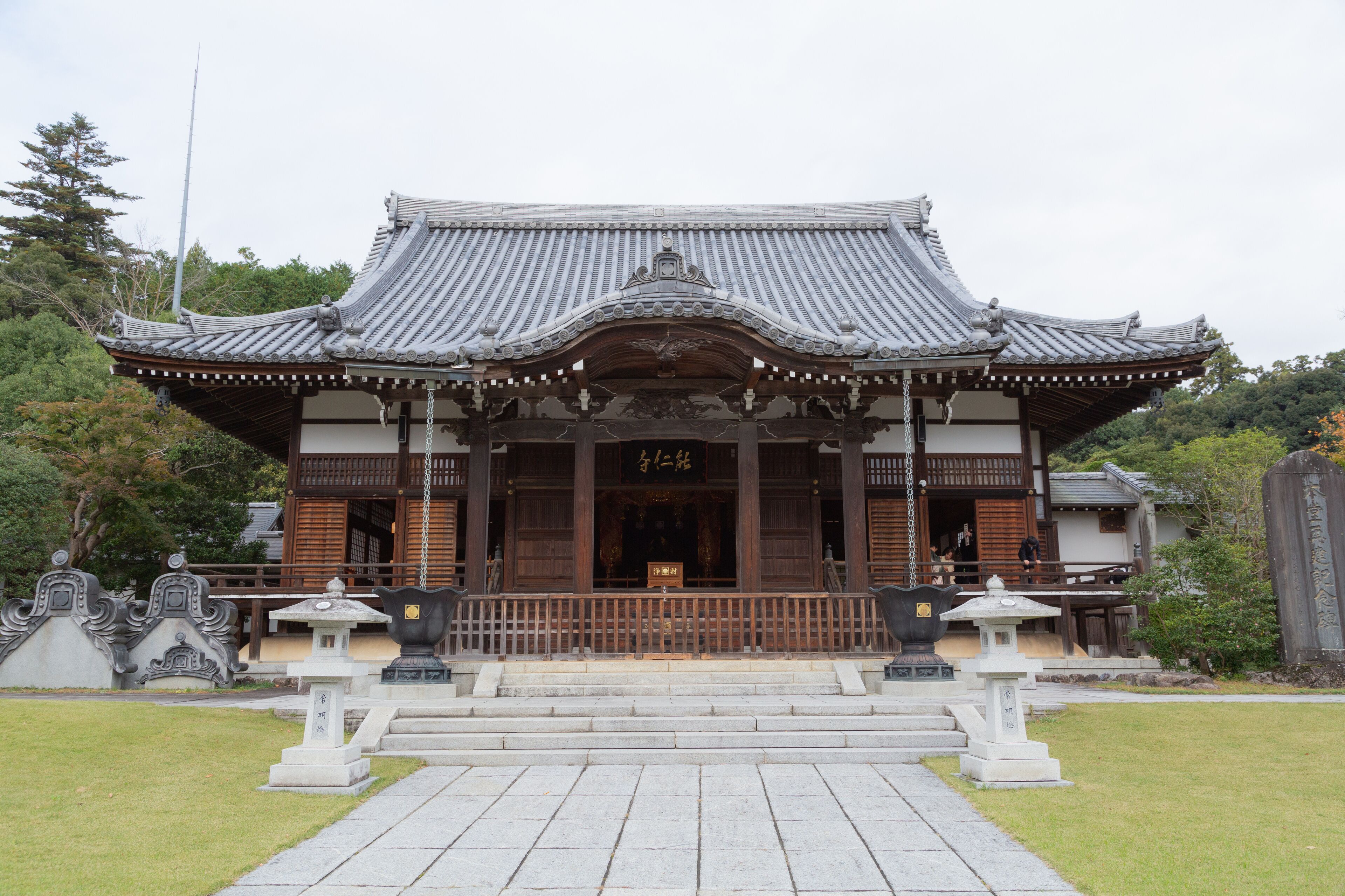 A traditional Japanese temple with a tiled roof, wooden structure, and stone steps leading to the entrance.