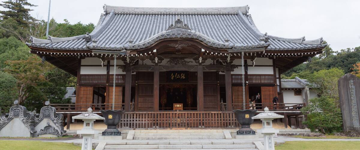A traditional Japanese temple with a tiled roof, wooden structure, and stone steps leading to the entrance.