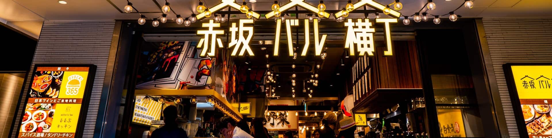 A restaurant entrance with hanging light bulbs and a sign with Japanese characters.