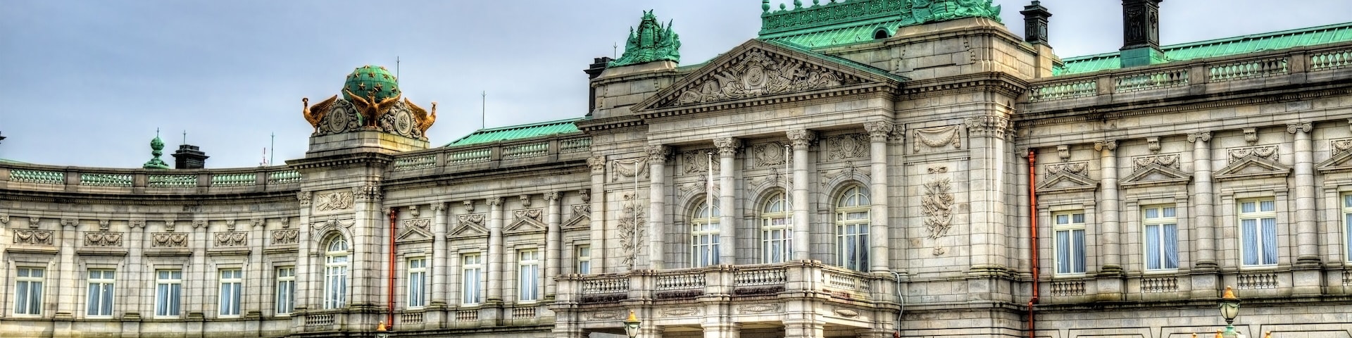 Um edifício histórico imponente com arquitetura elaborada, uma cúpula central e um amplo pátio.