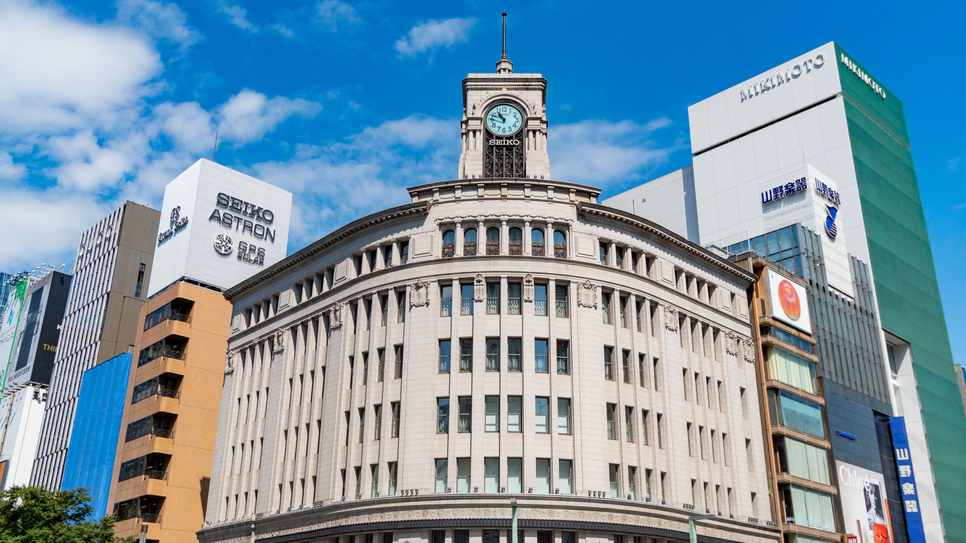 A historic building with a clock tower, surrounded by modern skyscrapers.