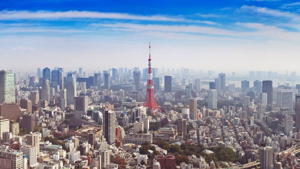 A densely packed cityscape with numerous high-rise buildings and a prominent red tower.