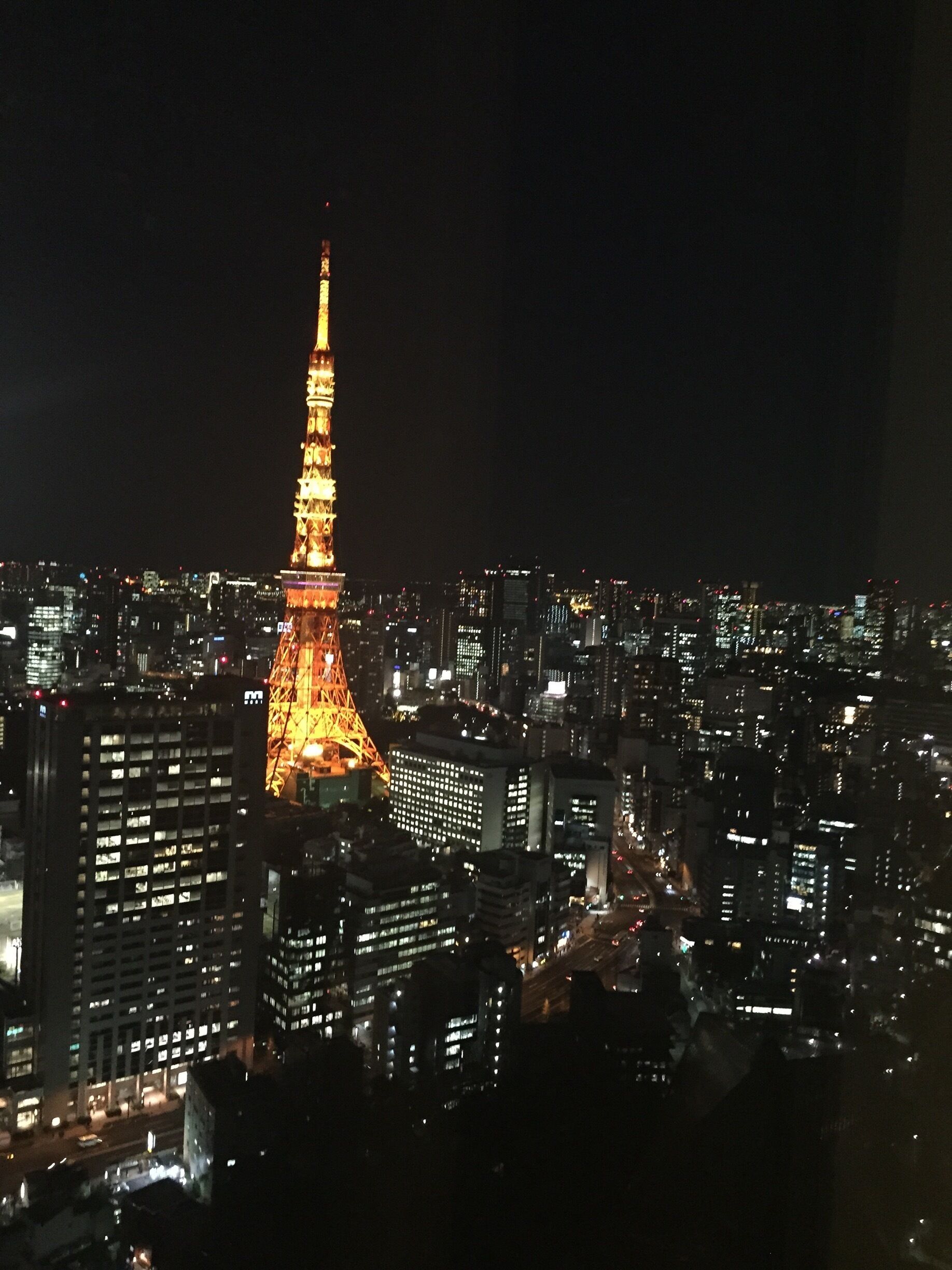 A cityscape at night with the illuminated Eiffel Tower in the center.