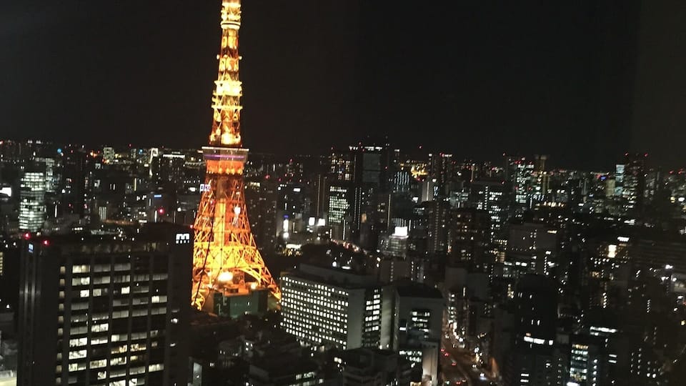 A cityscape at night with the illuminated Eiffel Tower in the center.