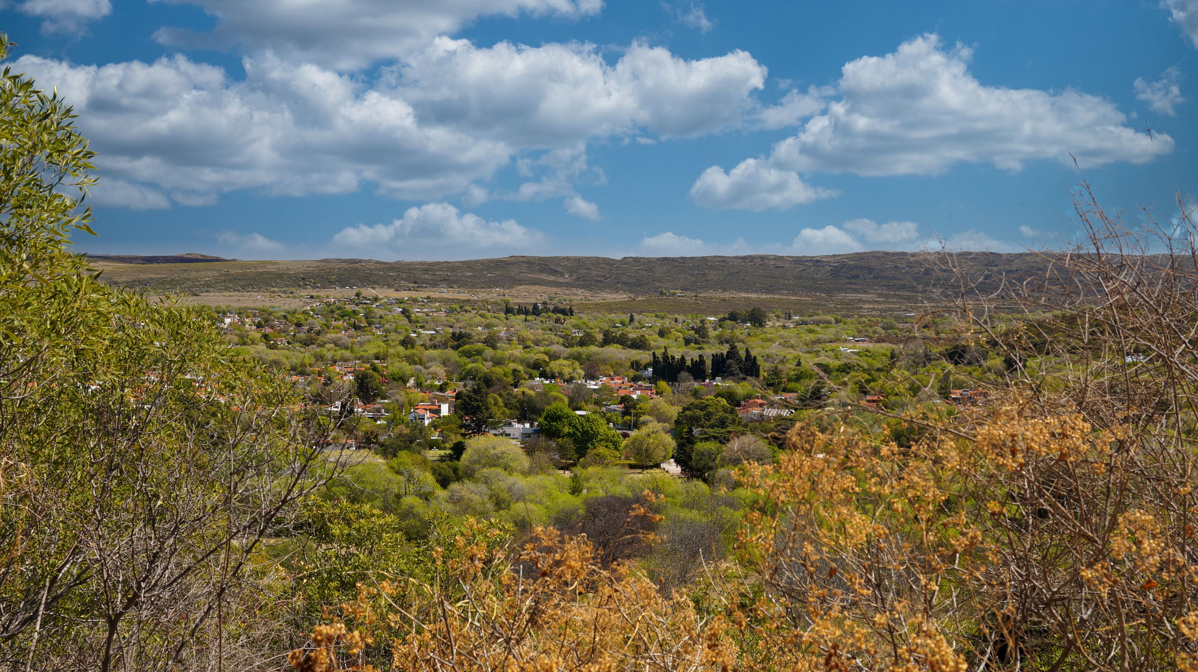A rural landscape with a village nestled among trees and hills.