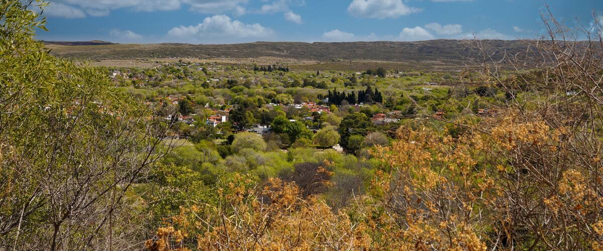 A rural landscape with a village nestled among trees and hills.