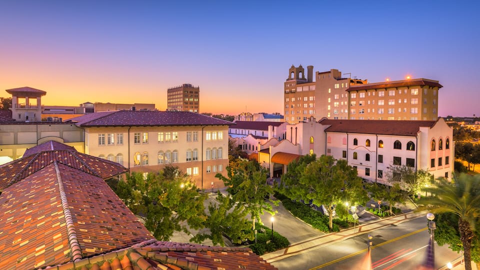 A cityscape at dusk with historic buildings, a prominent church tower, and a well-lit street.