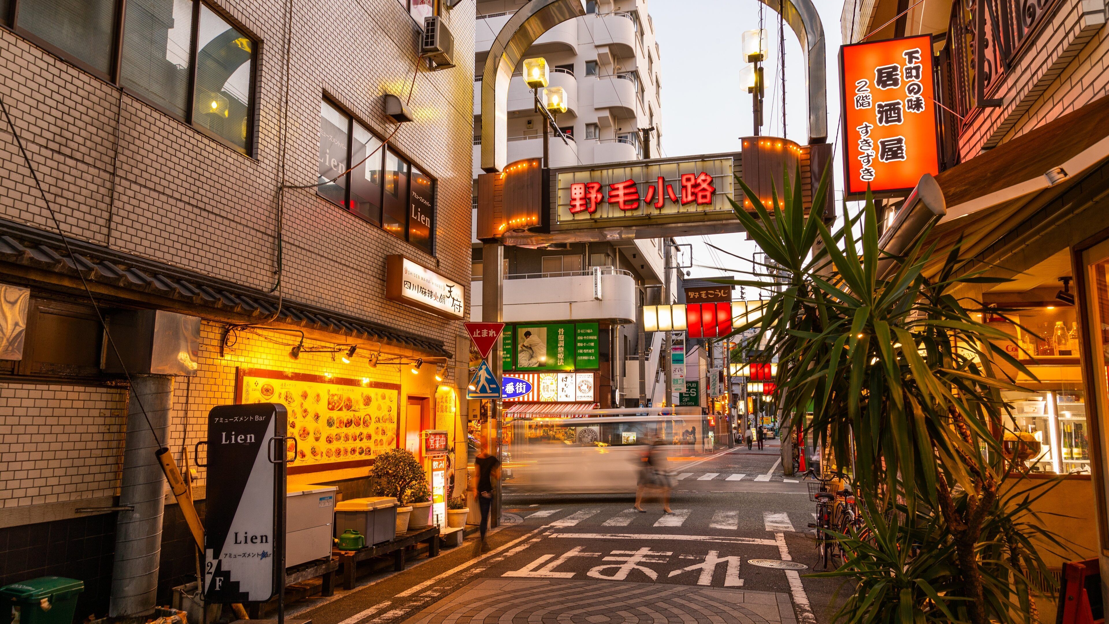 A narrow street with shops and a pedestrian crossing.