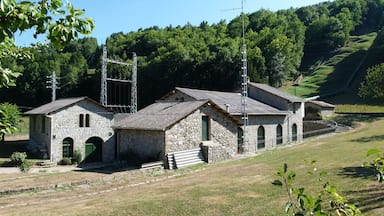 A stone building with a metal structure in a hilly area.