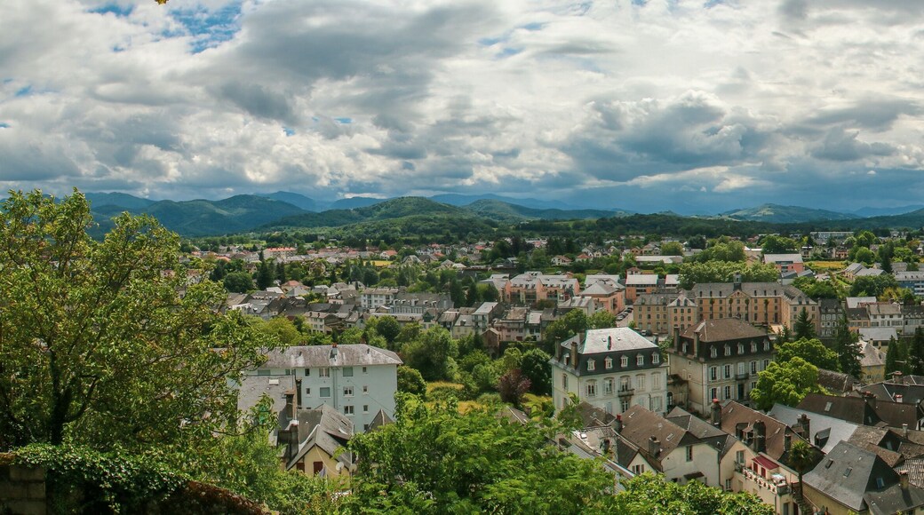 Vista panorámica de la ciudad de Oloron-Sainte-Marie en un nublado día de junio, Francia. Los tejados de los edificios y las verdes colinas al fondo.