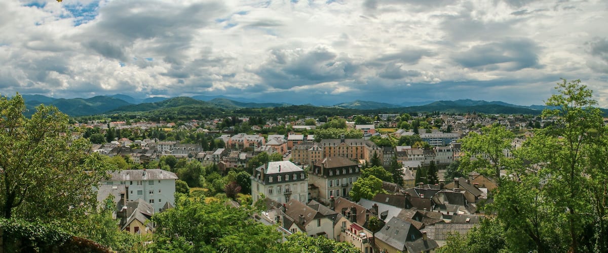 A town nestled among green hills under a cloudy sky.