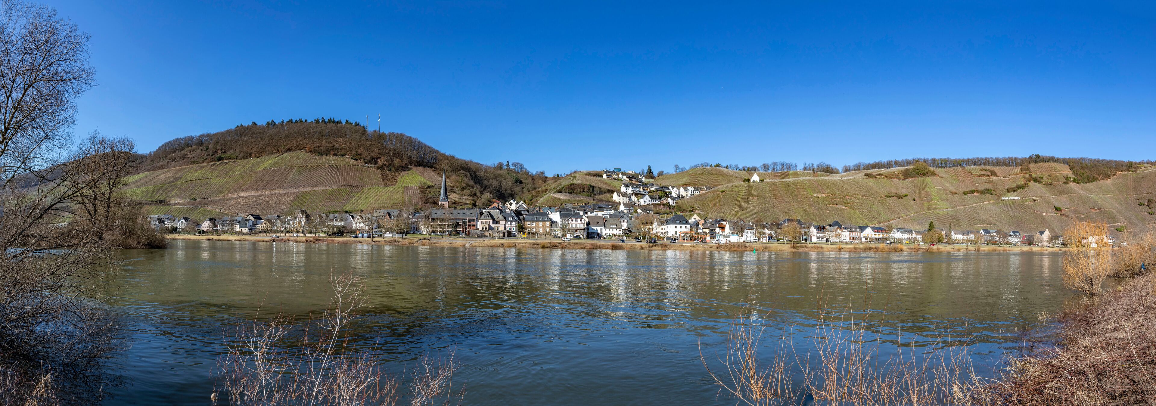 A lakeside village with houses, a church, and rolling hills.