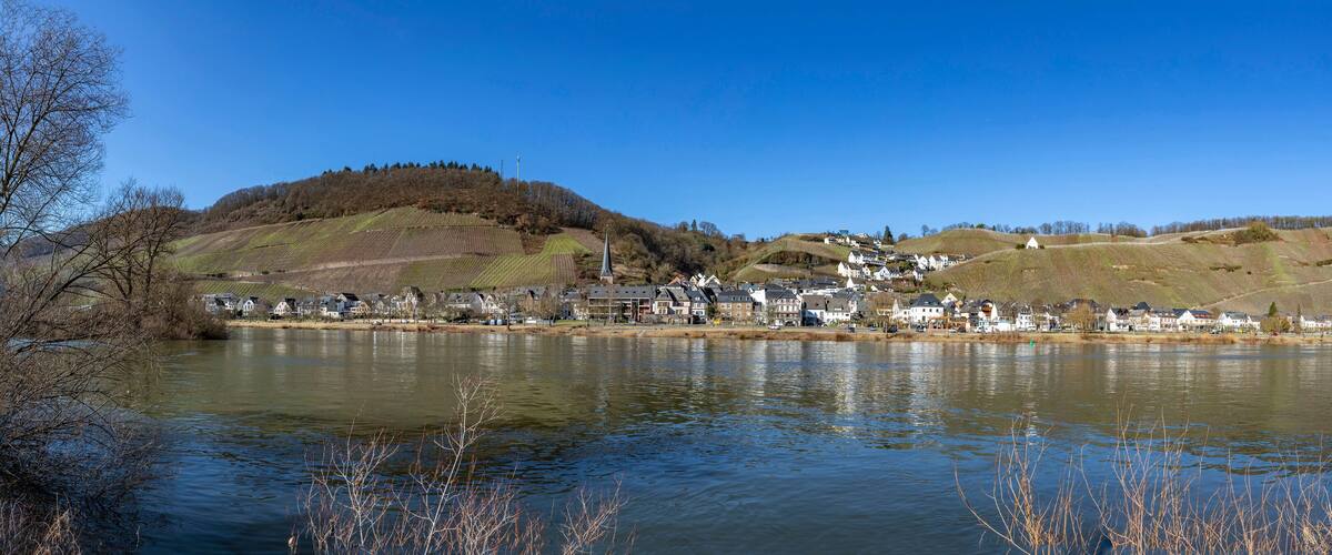 A lakeside village with houses, a church, and rolling hills.