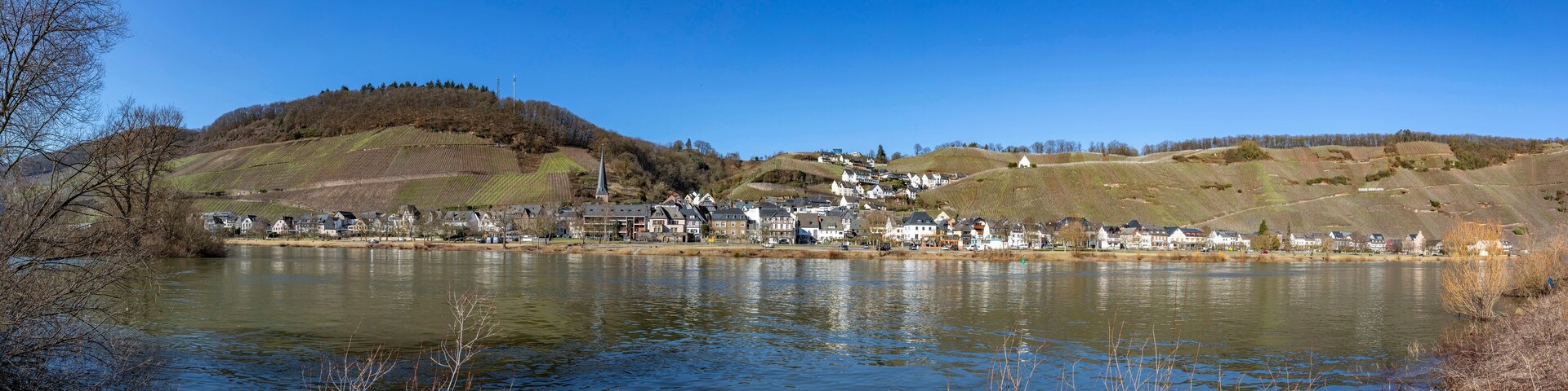 A lakeside village with houses, a church, and rolling hills.