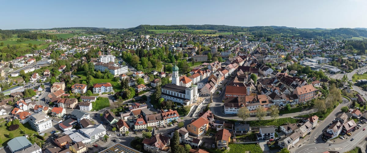 A densely populated town with a mix of residential and commercial buildings, surrounded by green hills.